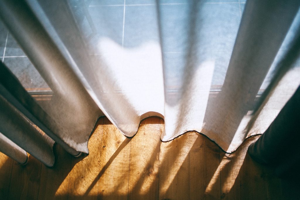 photo du soleil qui passe a travers des rideaux blanc ajusté à la taille du mur